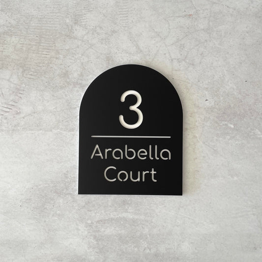 Black arch-shaped house number sign grey concrete background