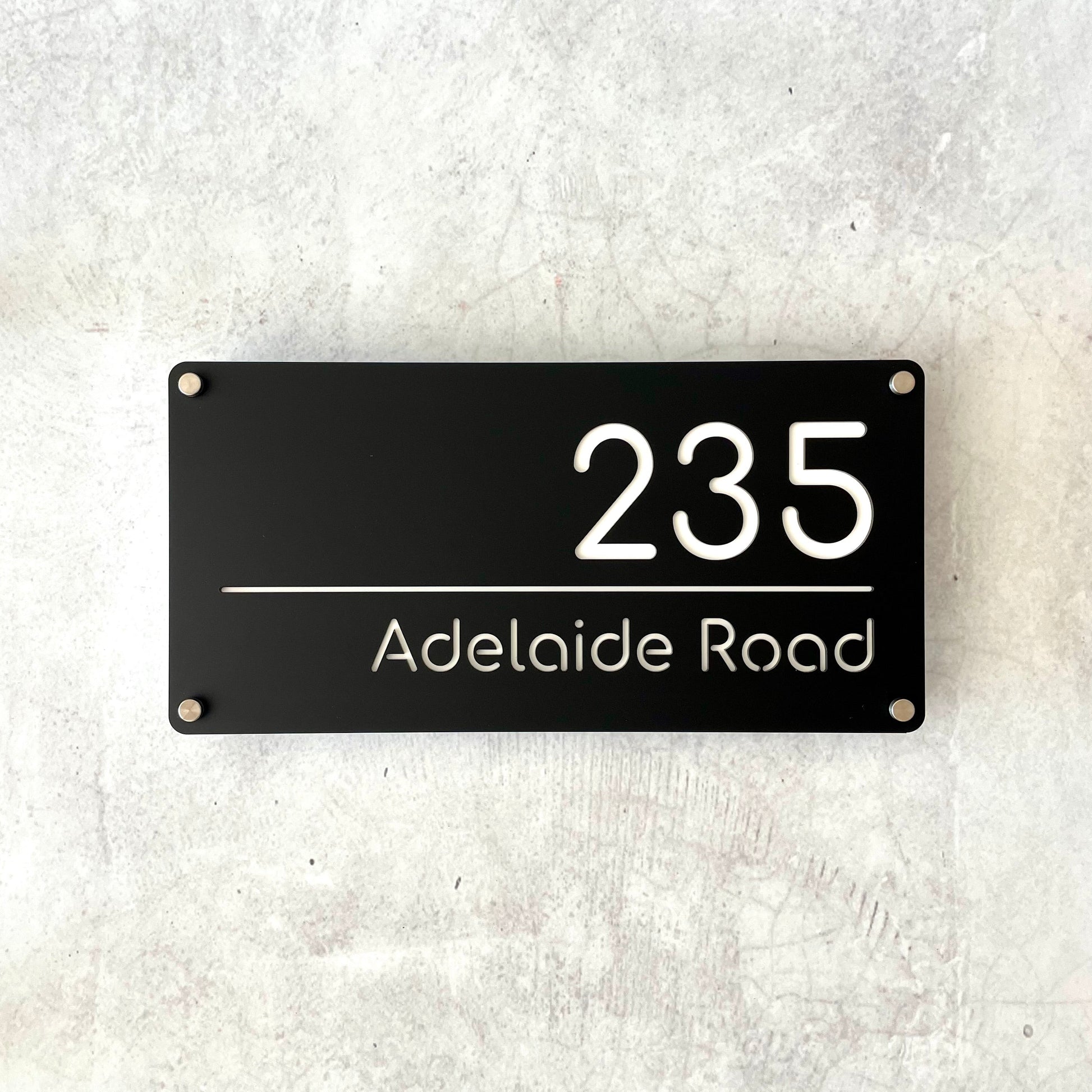 A floating black rectangular house number sign with white text