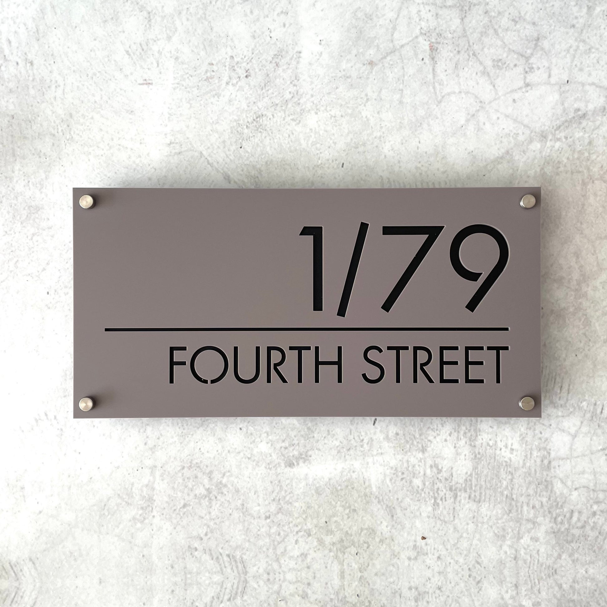 Gray house number sign with black text on a textured wall.