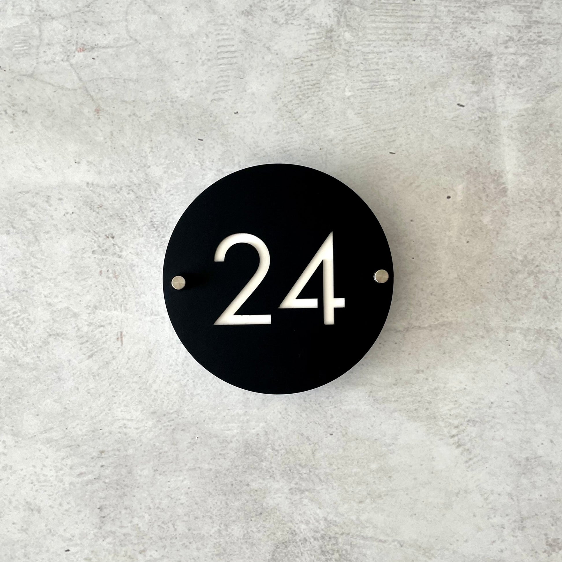 Black circular house number '24' with 20cm diameter and standoff screws