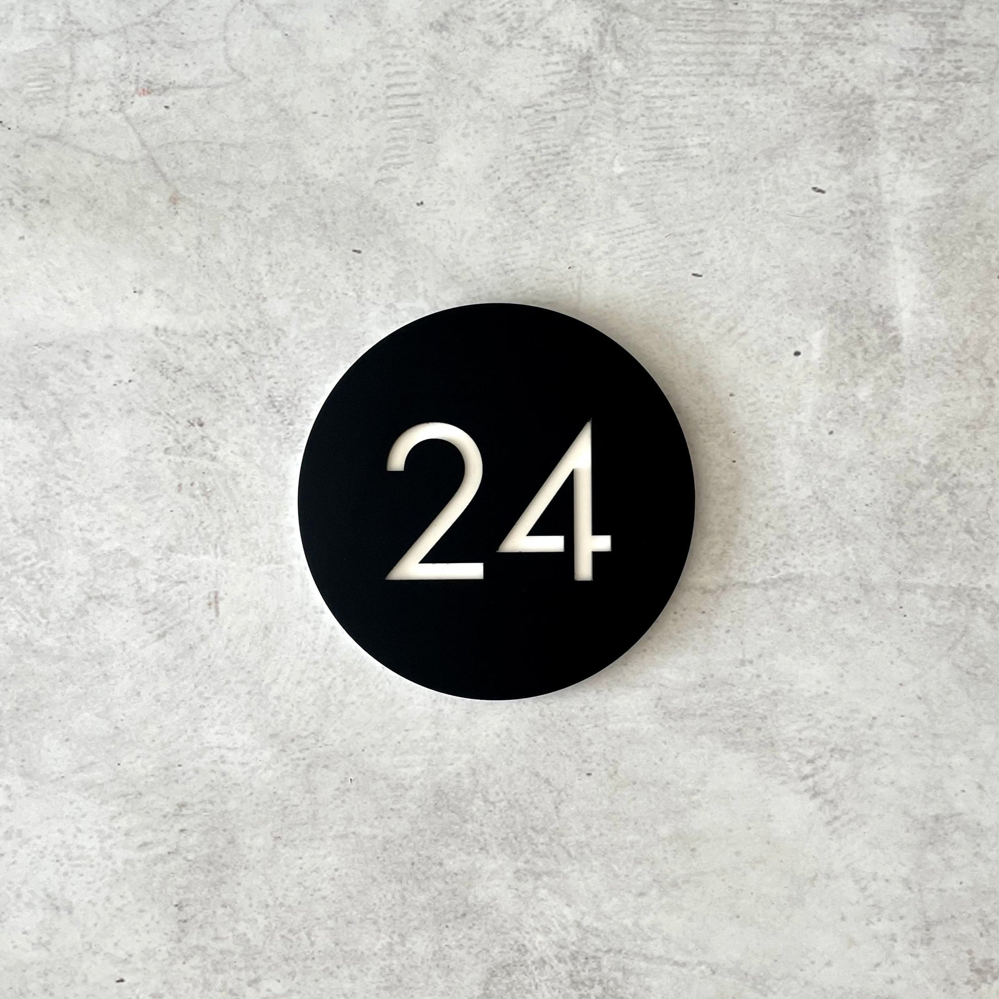 Black circular acrylic house numbers on a grey textured background