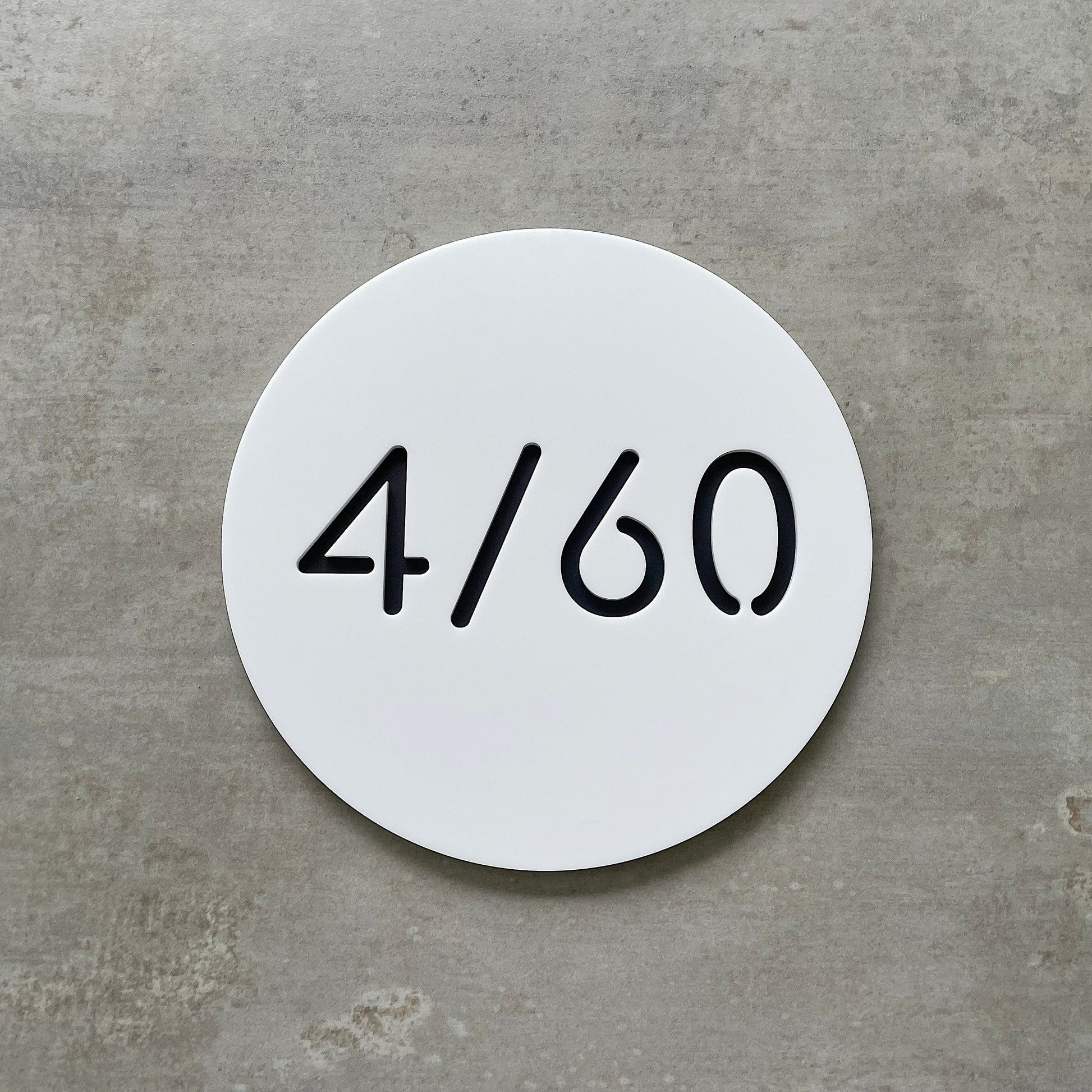 Round white plaque with unit number text on a grey background