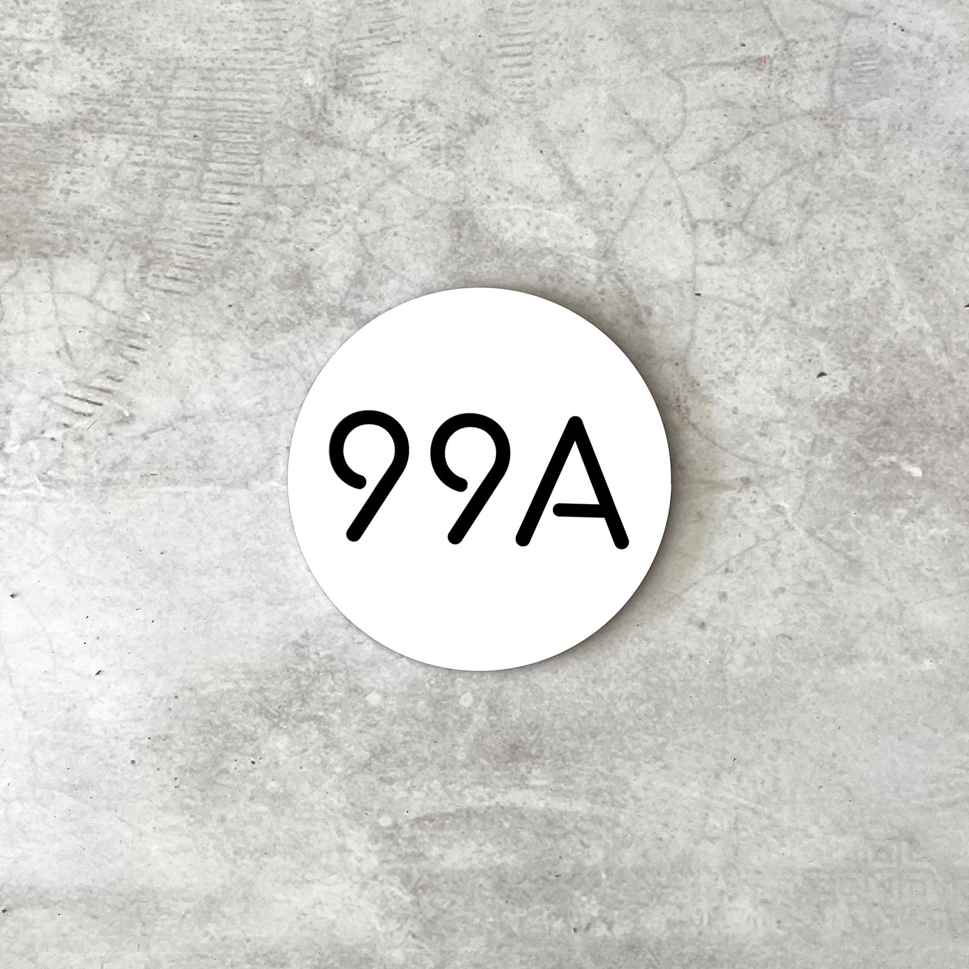 Premium round white house number on a grey concrete background