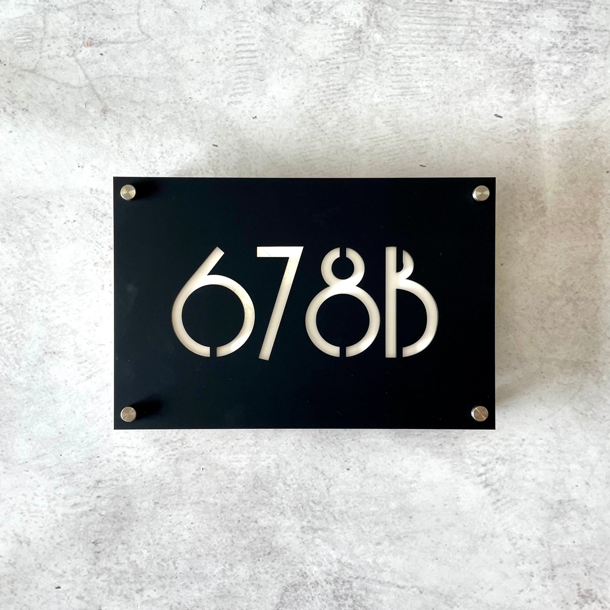 Art deco style house number in black with white lettering, mounted with standoff screws