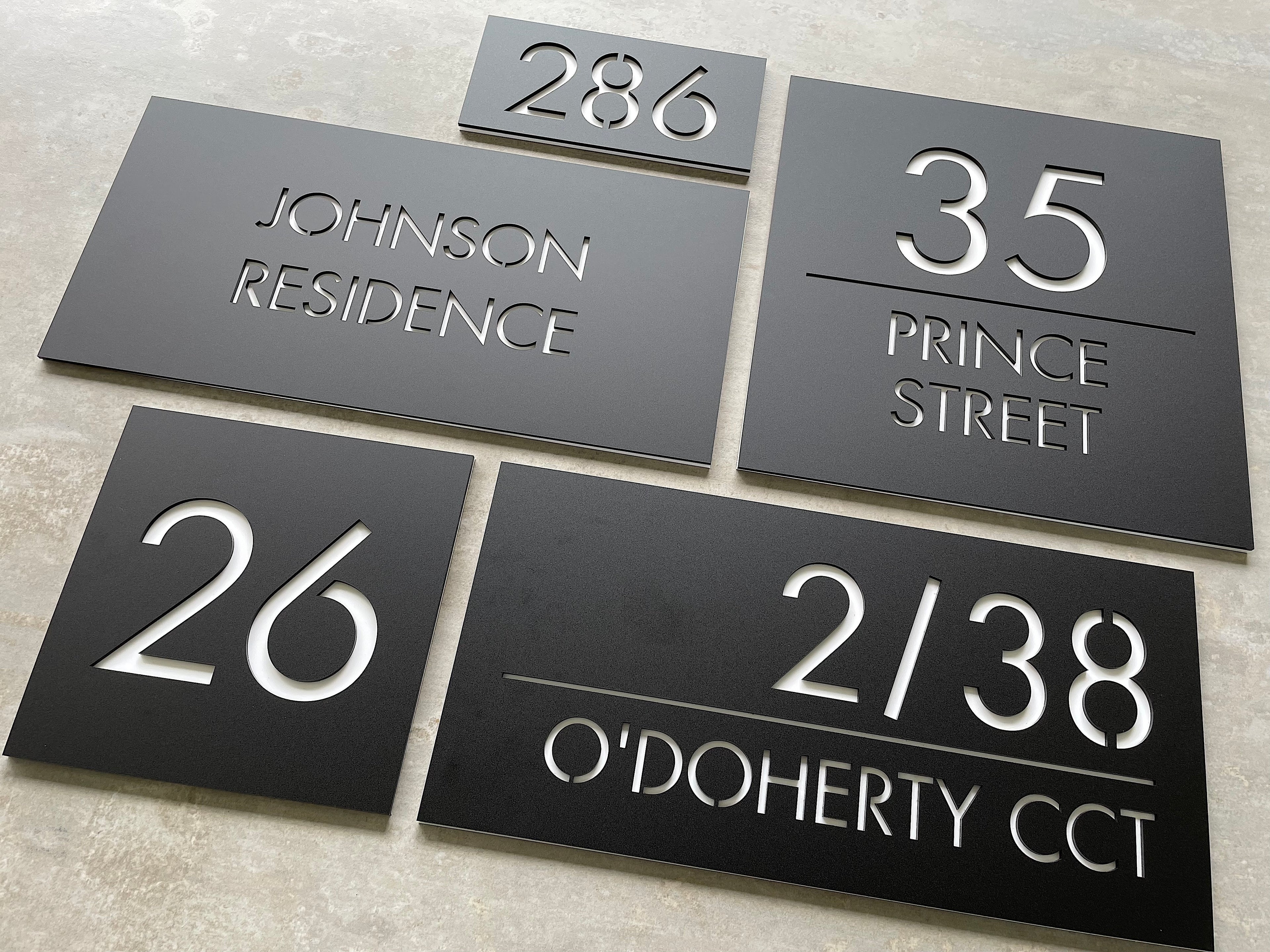A selection of custom acrylic house numbers in various styles, colours, and shapes displayed together