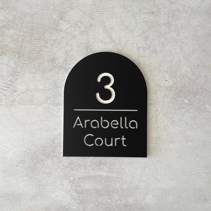 Black arch-shaped house number sign grey concrete background