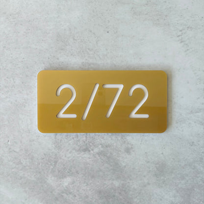 Gold apartment numbers with '2/72' text on a gray textured background