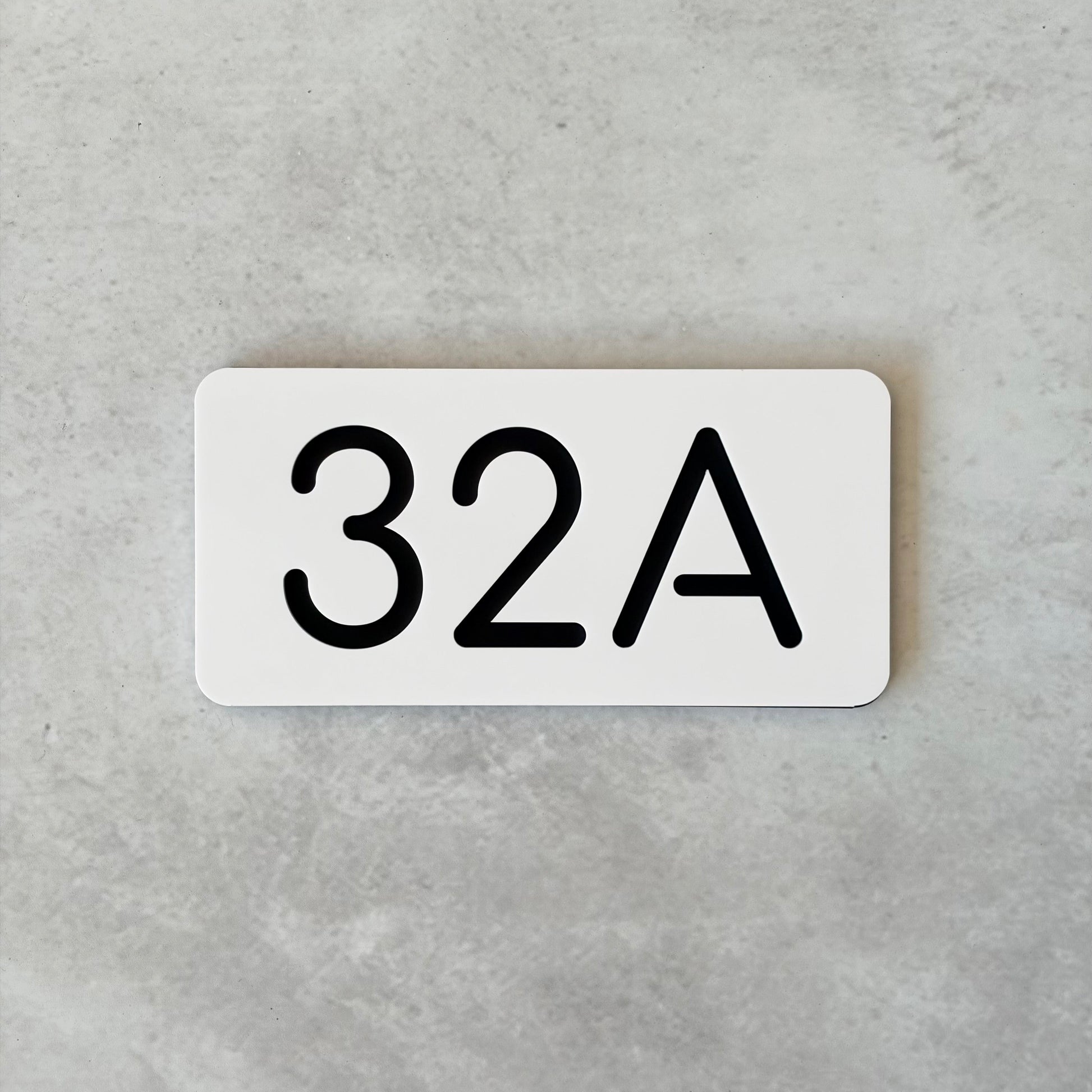 White rectangular unit sign with black text '32A' on a gray background