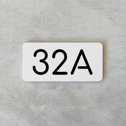White rectangular unit sign with black text '32A' on a gray background