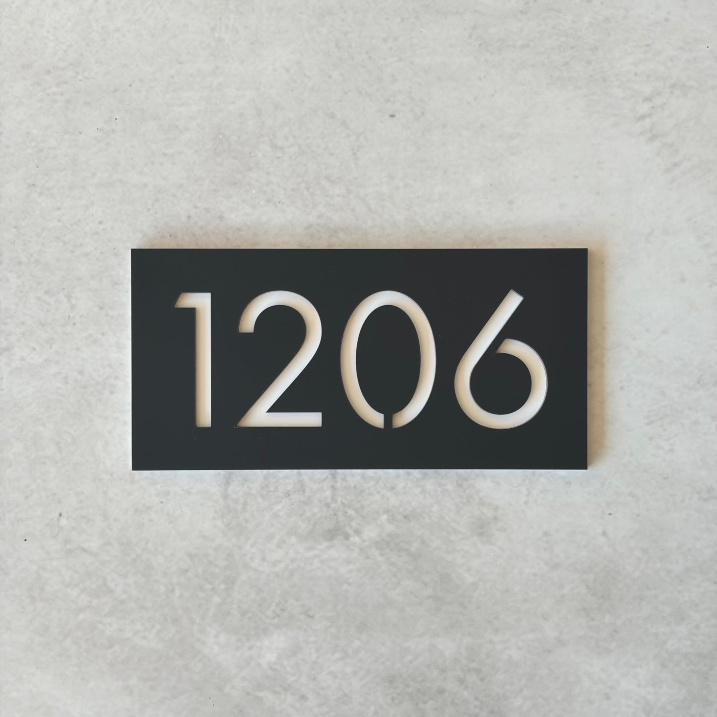 Charcoal rectangular plate with white unit numbers on a grey background
