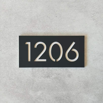 Charcoal rectangular plate with white unit numbers on a grey background