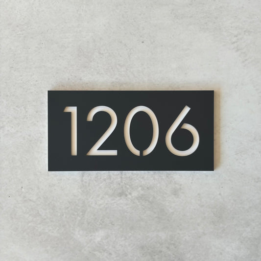 Charcoal rectangular plate with white unit numbers on a grey background