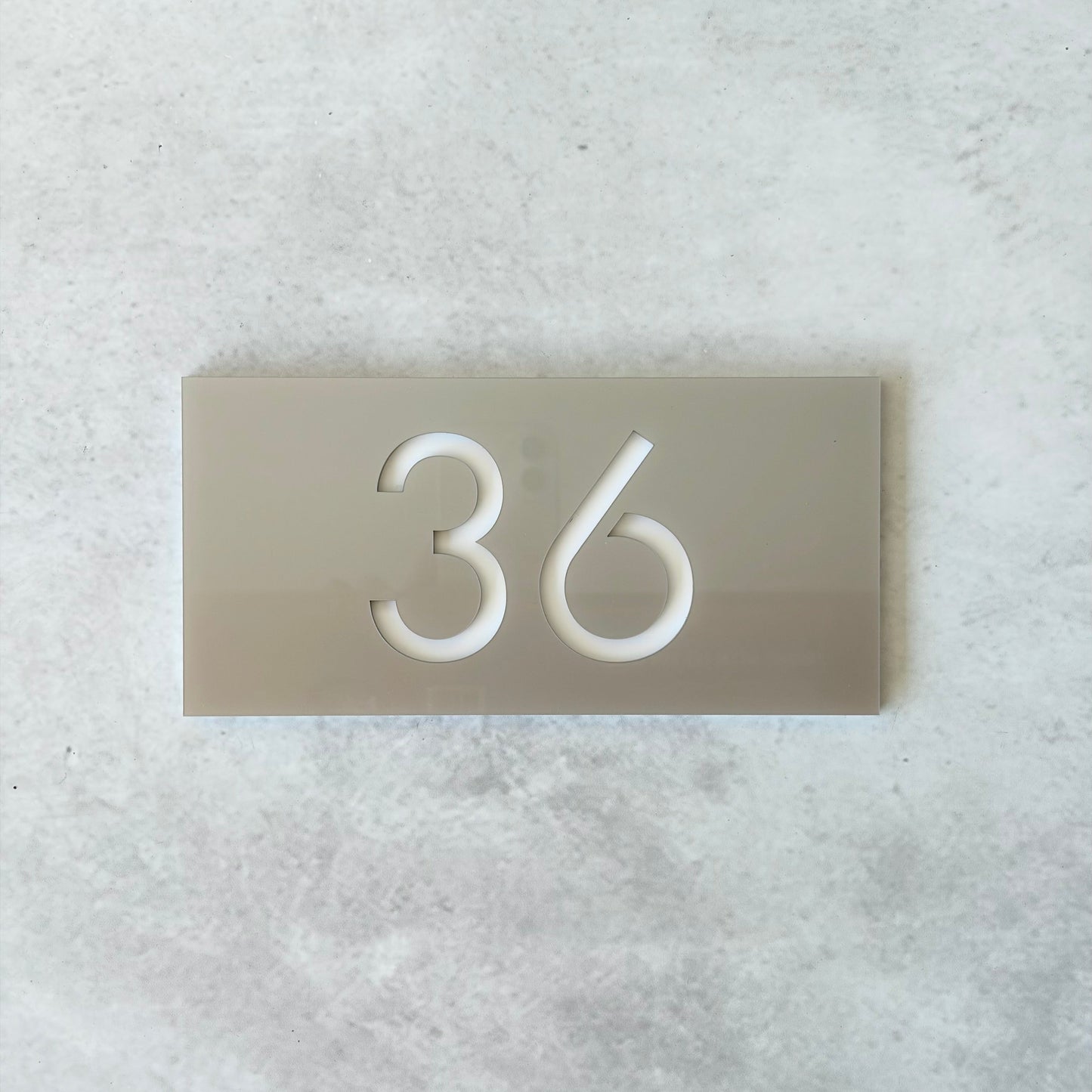 Apartment number on a metallic silver plate against a light grey background
