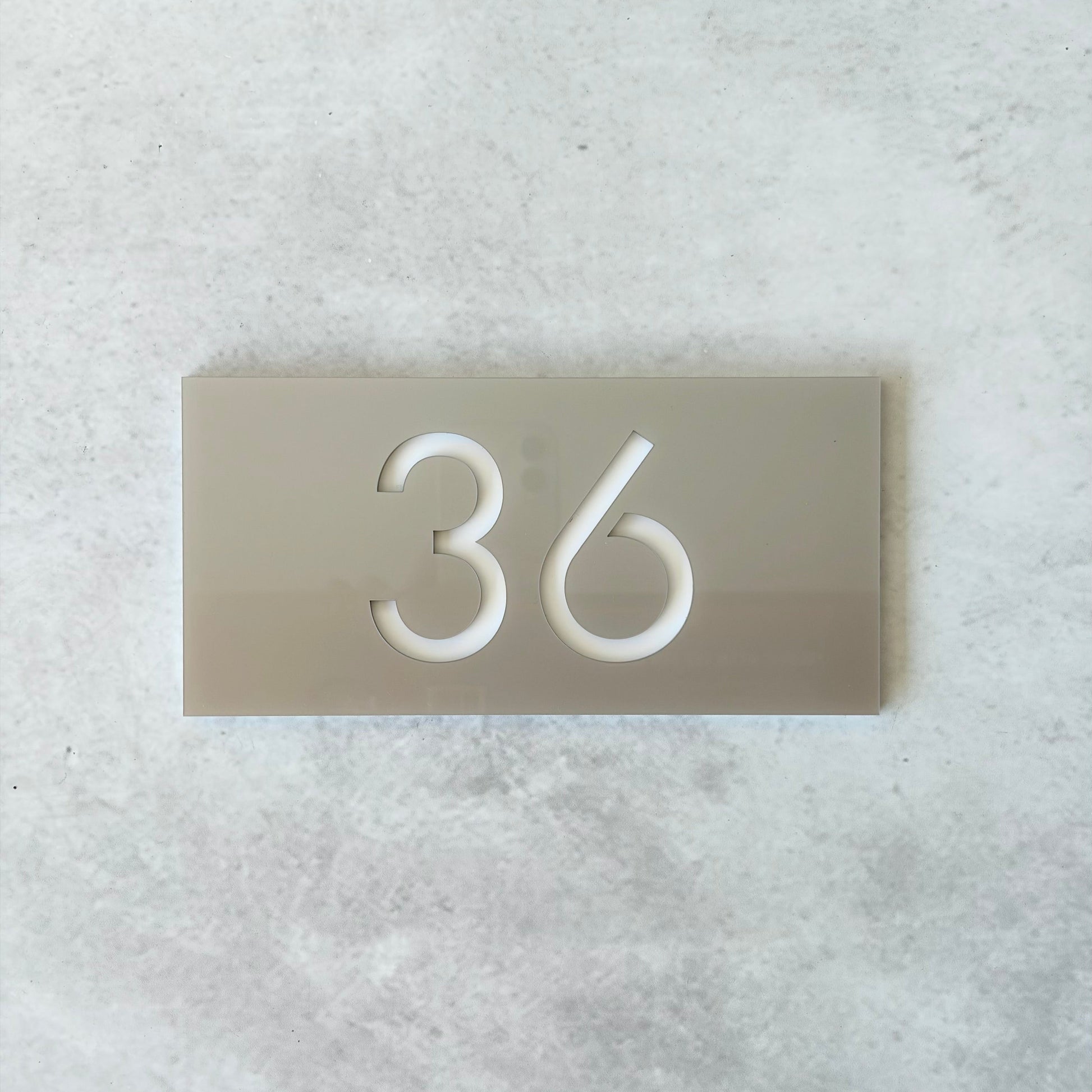 Apartment number on a metallic silver plate against a light grey background