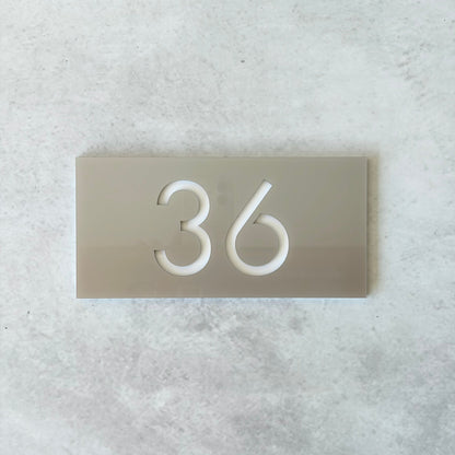 Apartment number on a metallic silver plate against a light grey background