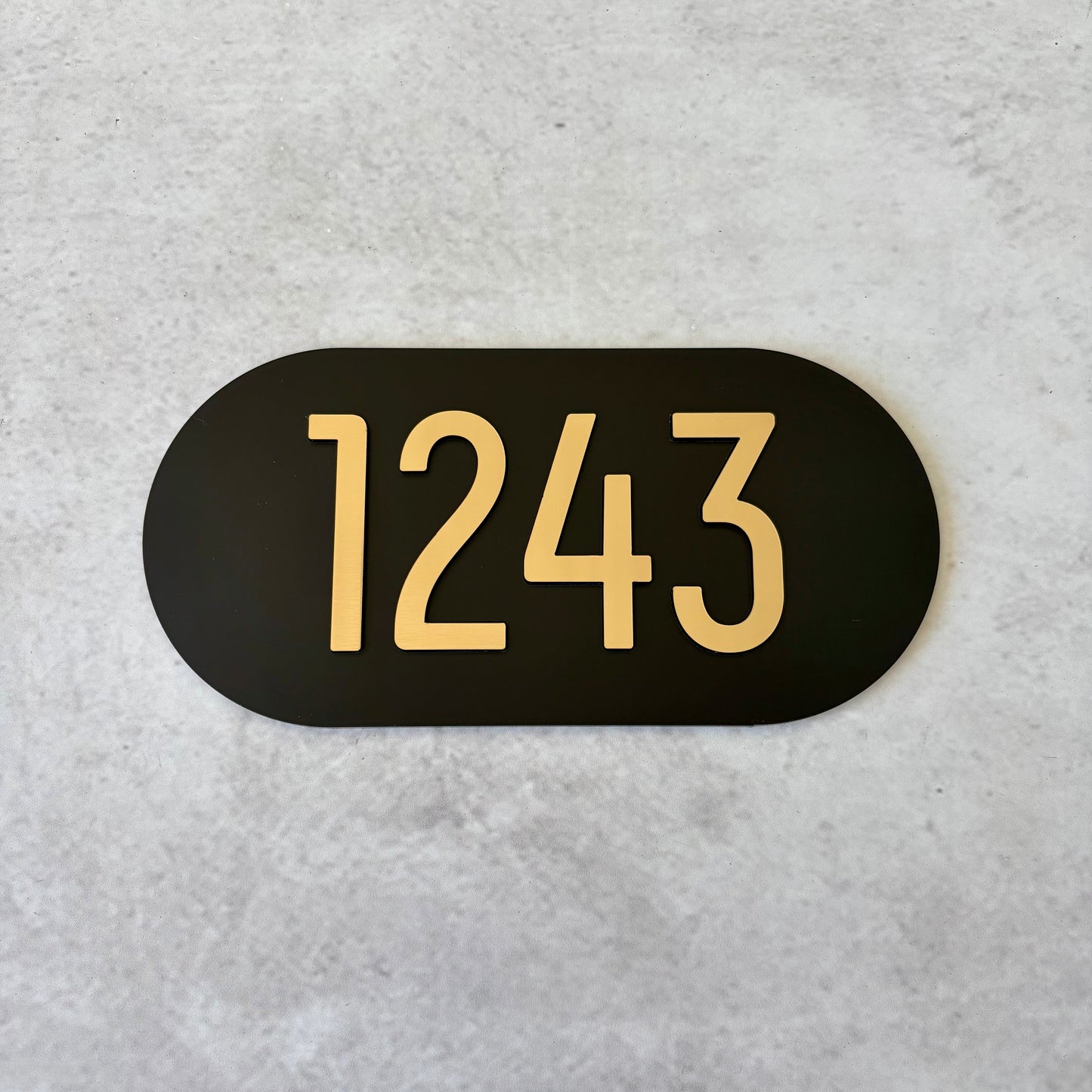 Black oval sign with brushed gold unit numbers