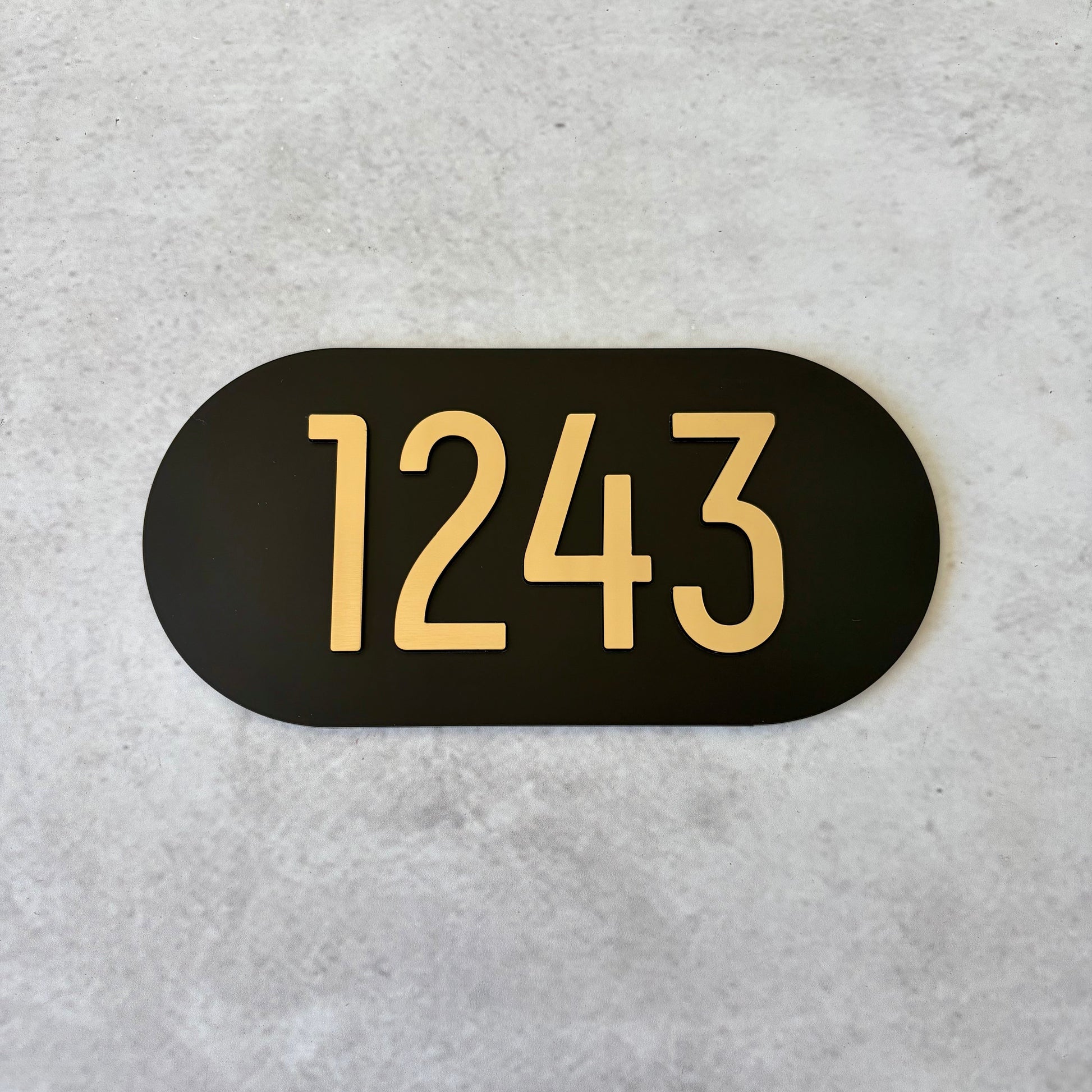 Black oval sign with brushed gold unit numbers