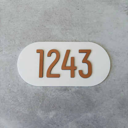 Oval-shaped apartment number plate with '1243' on a grey background
