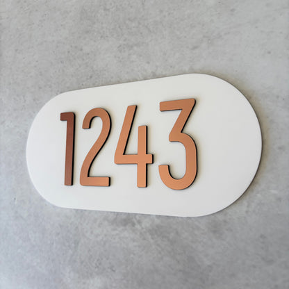 brushed copper unit number on white oval plaque