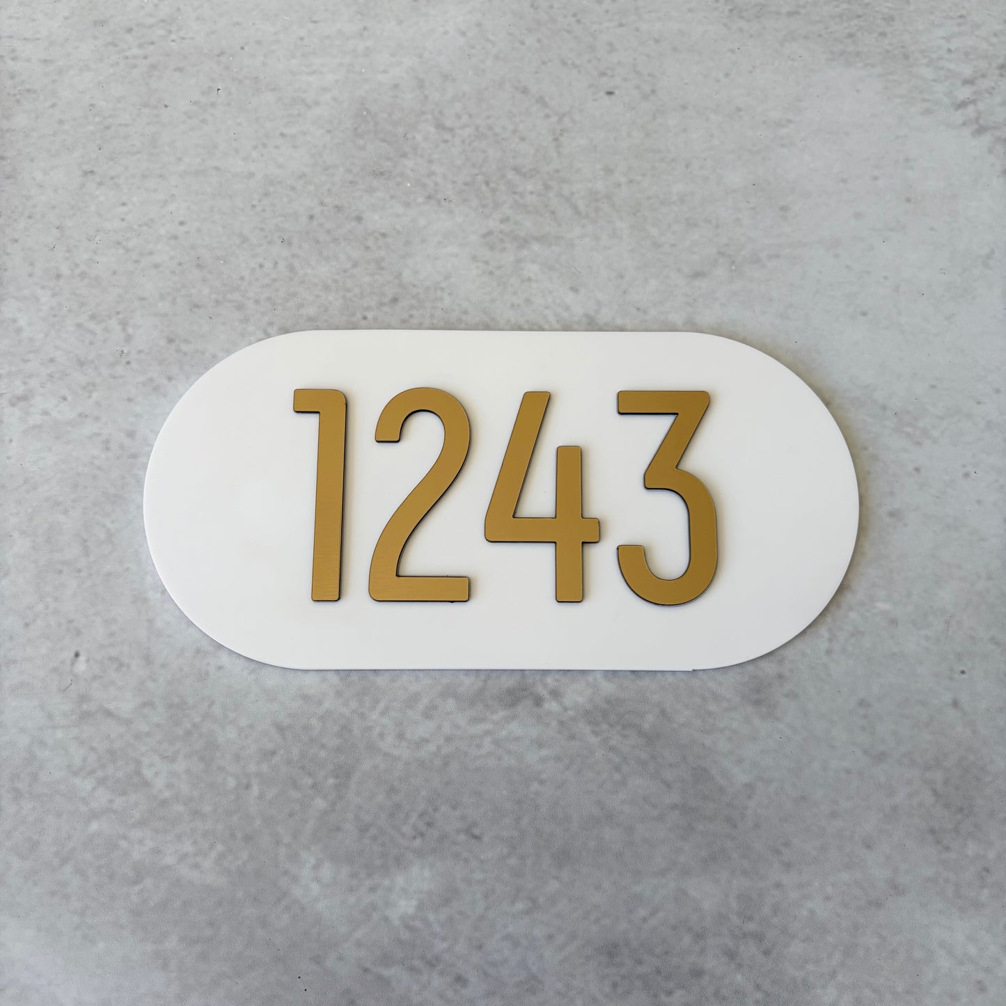 brushed gold apartment numbers on white oval plaque