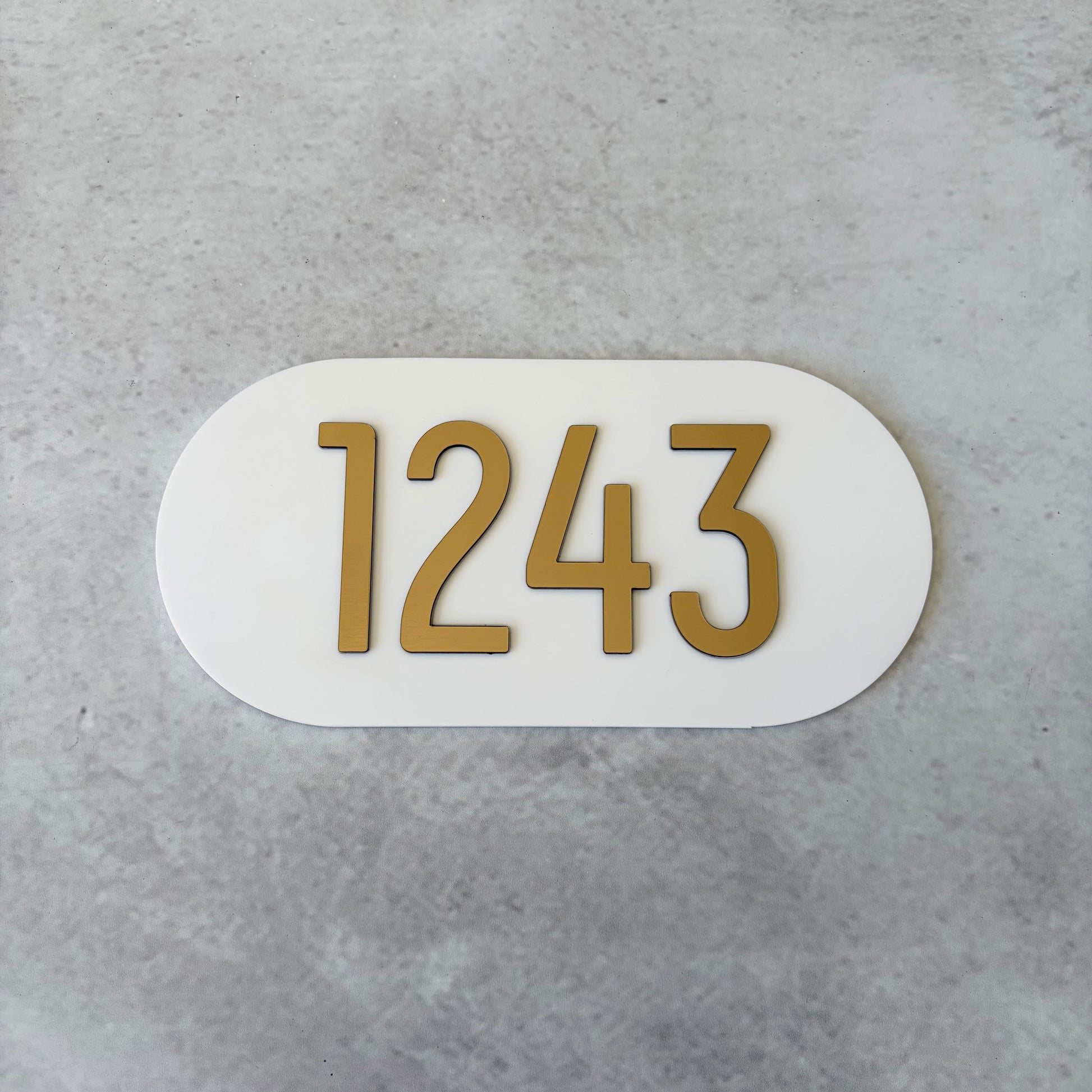 brushed gold apartment numbers on white oval plaque