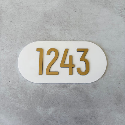 brushed gold apartment numbers on white oval plaque